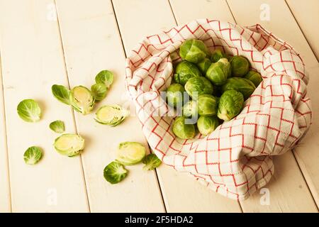 Ein paar frische rohe Rosenkohl-Sprossen in Stofftuch auf Weißer Holztisch Stockfoto