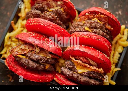 Set aus vier hausgemachten riesigen Doppel becon Käse Burger. Serviert mit pommes frites auf Holzbrett. Stockfoto