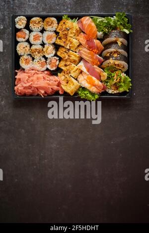 Sushi-Tablett zum Mitnehmen aus Kunststoff mit verschiedenen Rollen und Platz für Kopien. Konzept für Speisen zum Mitnehmen. Stockfoto