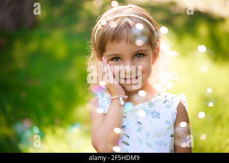 Süßes, glückliches, lächelndes fünfjähriges Mädchen, das auf dem Gras liegt Stockfoto