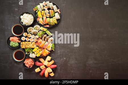 Verschiedene Sushi-Gerichte auf dunklem Hintergrund. Blick von oben auf Meeresfrüchte, verschiedene Maki-Brötchen Stockfoto