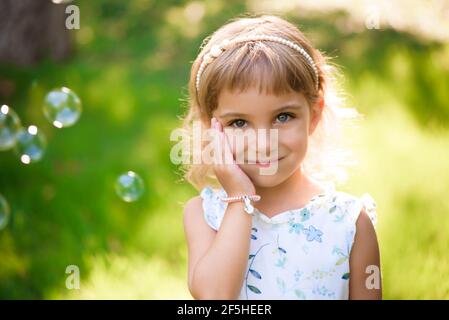 Süßes, glückliches, lächelndes fünfjähriges Mädchen, das auf dem Gras liegt Stockfoto