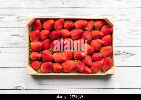 Köstliche rote Erdbeeren dicht in einer Holzkiste auf angeordnet Ein weißer Holzhintergrund Stockfoto