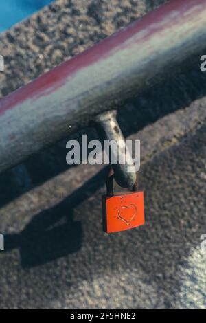 An einem hängt ein rotes Vorhängeschloss, das mit einem Herz eingraviert ist Handlauf einer Treppe Stockfoto