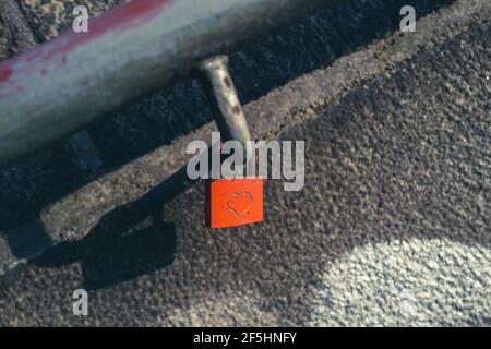 An einem hängt ein rotes Vorhängeschloss, das mit einem Herz eingraviert ist Handlauf einer Treppe Stockfoto