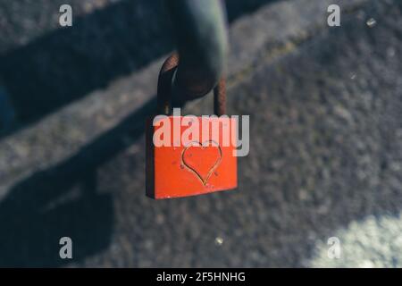 An einem hängt ein rotes Vorhängeschloss, das mit einem Herz eingraviert ist Handlauf einer Treppe Stockfoto