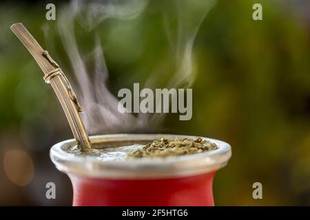 Horizontale Nahaufnahme Von Hot Traditional South American, Koffein-Reiche Infused Drink Mate (Yerba Mate) In Red Ceramic Gourd. Steaming Mate Infusion Stockfoto