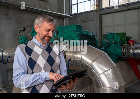 Geschäftsperson, Die Ein Digitales Tablet In Der Fabrikhalle Verwendet. Ingenieur, der im Fernwärmekraftwerk steht. Digitales Technologiekonzept. Industrie 4,0 Stockfoto