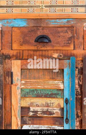 Ein bemalter Holzstuhl, von hinten gesehen, steht an einem geschmückten Schreibtisch mit einer Schublade und geometrischen Details Stockfoto