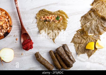 Yaprak sarmasi ist ein traditionelles türkisches Gericht, das durch das Einwickeln von Reisfüllung mit Traubenblättern hergestellt wird. Flat Lay-Bild zeigt die Zutaten während der Vorbereitung Stockfoto