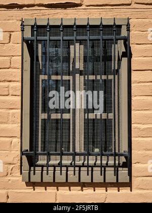 Ein Fenster aus altem adobe mit ornamentalen Eisenstangen. Stockfoto