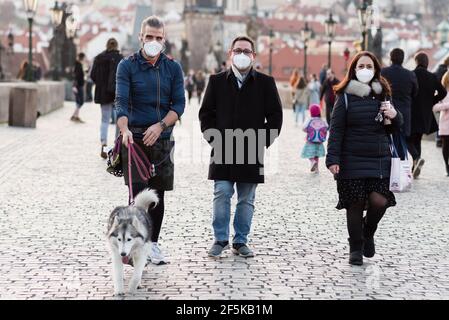 Prag, Tschechische Republik. März 2021, 26th. Zwei Männer und eine Frau mit Gesichtsmasken als vorbeugende Maßnahme gegen die Ausbreitung des Coronavirus gehen mit einem Hund entlang der Karlsbrücke in Prag. (Foto von Tomas Tkacik/SOPA Images/Sipa USA) Quelle: SIPA USA/Alamy Live News Stockfoto