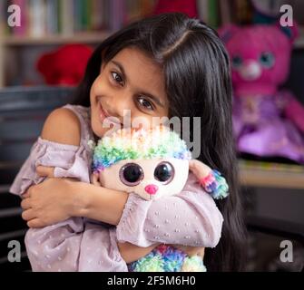 Nahaufnahme Studio Portrait eines lächelnden indischen Kindes, das ein Stofftier kuschelt. Vorschule Kinder Glück Konzept Stockfoto