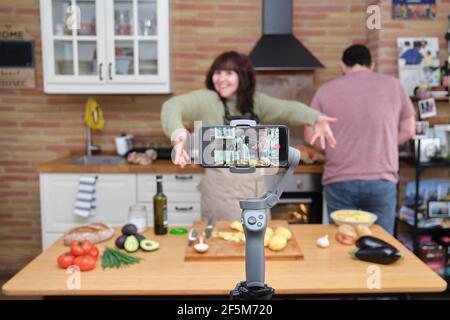 Junge Frau, die mit ihrem Smartphone ein Video für ihren Kochkanal aufzeichnet. Content Creator und Influencer. Stockfoto
