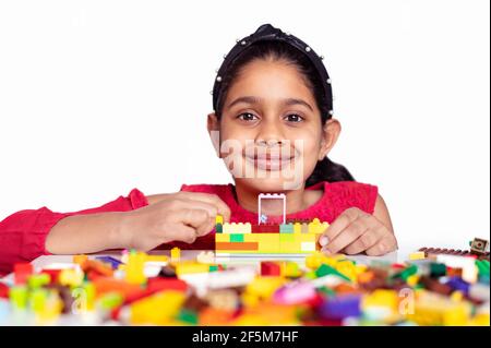 Ein nettes kleines indisches Mädchen, das mit bunten Spielzeugbausteinen spielt und Spaß hat. Kinder Entwicklung Aktivitätskonzept. Frühes Lernen Stockfoto