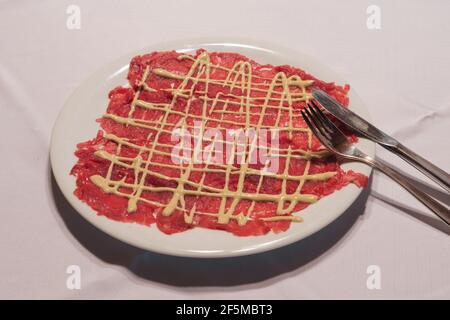 Carpaccio aus Rind mit Mayonnaise-Sauce im klassischen Cipriani-Stil Eine weiße Platte Stockfoto