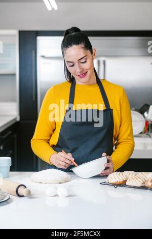 Lateinische Frau steht in der Küche und knetet Teig zu backen Conchas traditionelles mexikanisches Brot Stockfoto