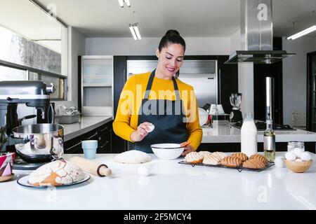 Lateinische Frau steht in der Küche und knetet Teig zu backen Conchas traditionelles mexikanisches Brot Stockfoto