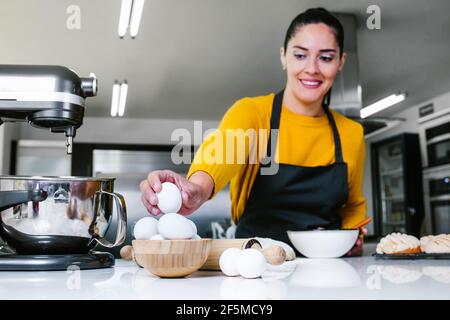 Lateinische Frau steht in der Küche und knetet Teig zu backen Conchas traditionelles mexikanisches Brot Stockfoto