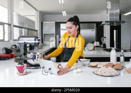 Lateinische Frau steht in der Küche und knetet Teig zu backen Conchas traditionelles mexikanisches Brot Stockfoto