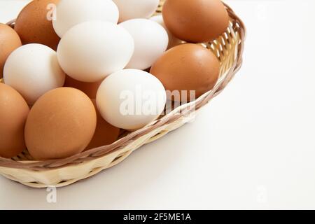 Weiße und braune Eier im Weidenkorb auf weißem Hintergrund. Ostern. Stockfoto