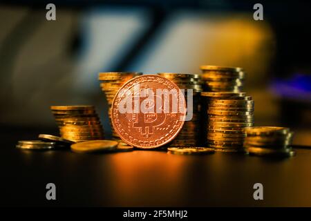 Geringe Schärfentiefe (selektiver Fokus) Bild mit einer Bitcoin-Metallmünze in der Nähe anderer Metallmünzen - Kryptowährung Konzept. Stockfoto