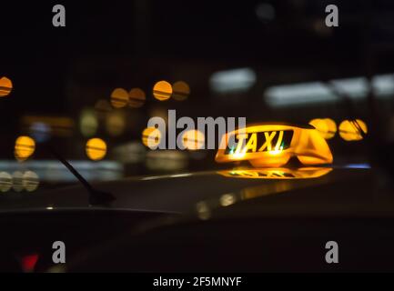 Beleuchtetes Schild Taxi auf dem Dach des Autos an Nacht Stockfoto