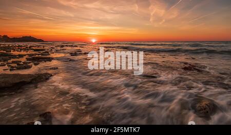 Atemberaubender Sonnenaufgang über dem Meer mit Wellen, die sich durch Bewegung verwischen Stockfoto