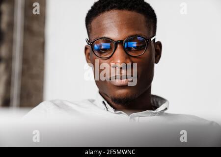 Afro american fokussierten jungen Mann in Brillen arbeiten mit Laptop In Innenräumen Stockfoto