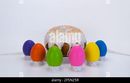 Osterbrot und bunte Eier auf weißem Hintergrund. Helle Eier mit einem festlichen Band gebunden. Stockfoto