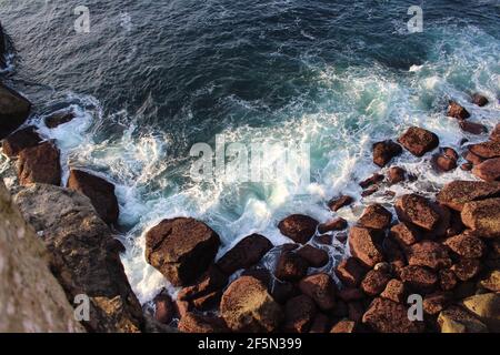 Wellen krachen auf Felsen am Fuße einer Klippe Stockfoto