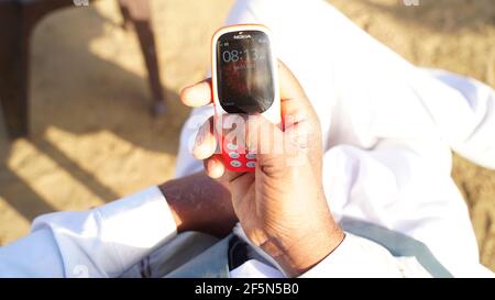 Rajasthan, Indien - 20. März 2021; EIN Mann hält Nokia Tastatur mobile Modell 3310 mit schwarzem Bildschirm isoliert auf weißem Hintergrund. Smartphone-Taste I drücken Stockfoto