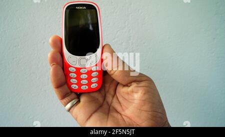 Rajasthan, Indien - 20. März 2021; EIN Mann hält Nokia Tastatur mobile Modell 3310 mit schwarzem Bildschirm isoliert auf weißem Hintergrund. Smartphone-Taste I drücken Stockfoto
