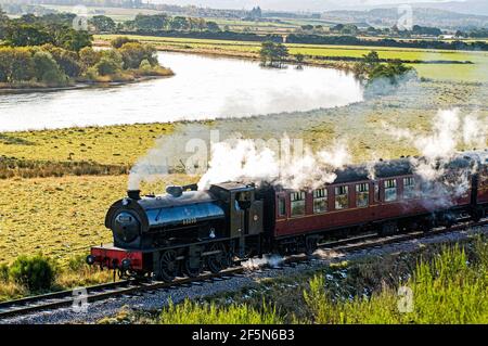 Die Strathspey Steam Railway in der Nähe des Bahnhofs Broom Hill, wenn sie den Fluss Spey entlang der malerischen Route passiert. Stockfoto