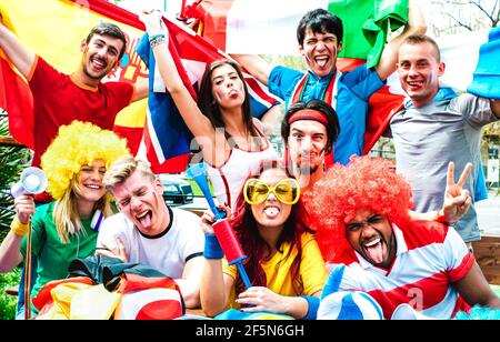 Junge Fußballfans, die beim Fußball mit internationalen Flaggen jubeln Match - Glückliche Menschen mit bunten T-Shirts Spaß zusammen Im Freien Stockfoto