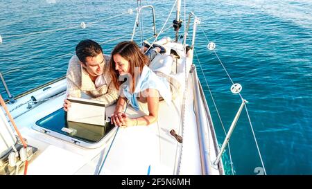 Junges Paar in der Liebe mit Spaß mit Tablet-pc auf Segelboot - Luxus Reisen Lebensstil und digitale Nomaden Konzept Auf exklusiver Yacht-Tour Stockfoto