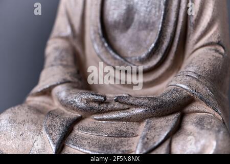 Hände der meditierenden Buddha Statue auf dunklem Hintergrund. Nahaufnahme. Stockfoto