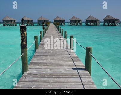 Hölzerner Pier, der zu den Water Villas im maledivischen Resort führt. Ein Spaziergang mit Türkismeer, Überwasser-Bungalows und Blue Sky auf den Malediven. Stockfoto