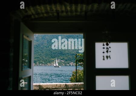 Blick vom Fenster auf die Berge, die Bucht und das Segelschiff. Stockfoto