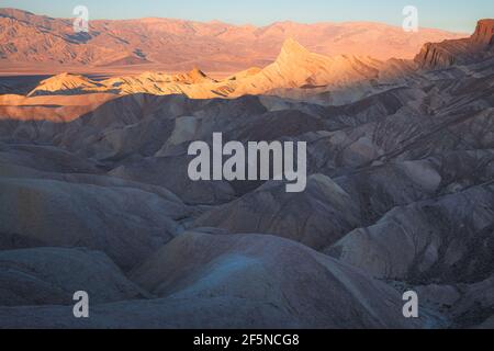 Golden Sonnenuntergang oder Sonnenaufgang Licht am Zabriskie Point und die Zerklüftete Sedimentgestein Gelände der Badlands Landschaft im Tod Valley Park National Park Stockfoto