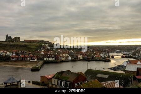 Ein Wintersonnenaufgang über Whitby Harbour, North Yorkshire, Großbritannien mit der Abtei im Hintergrund. Stockfoto