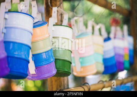 Stillleben mit mehrfarbigen Futterträger oder Tiffin-Träger, der am Holzstab hängt. Selektive Fokus Vintage Retro Thai Stil bunte Tiffin carrie Stockfoto