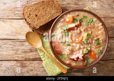 Hausgemachte Ricet Gerste und Bohnensuppe mit geräuchertem Fleisch und Gemüse aus der Nähe in einer Schüssel auf dem Tisch. Horizontale Ansicht von oben Stockfoto