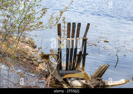 Ein alter hölzerner Lagerstuhl wurde an einem Flussufer ausgewaschen Nach dem Frühling brachte Hochwasser verheerende Schäden in der Gegend Stockfoto