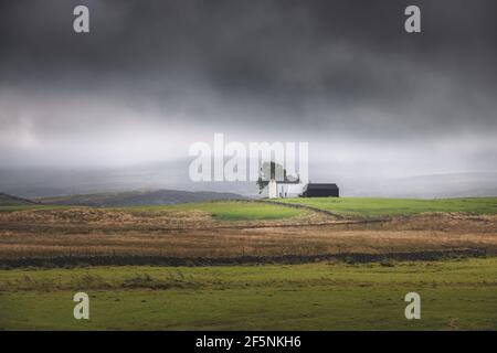 Einsamer, abgeschiedener Bauernhof auf einer stürmischen, launischen englischen Landschaft ländliche Landschaft in der North Pennines AONB, England Großbritannien. Stockfoto