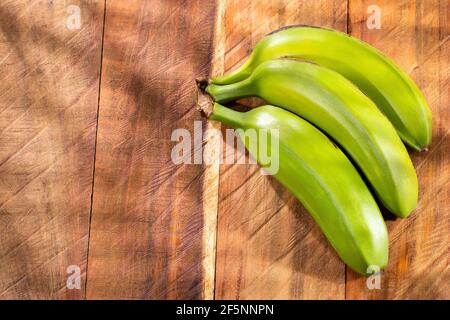 Bündel von grünen Bananen auf Holzhintergrund - Musa x Paradiesische Stadt Stockfoto