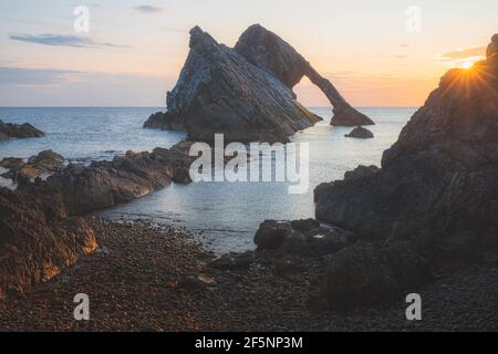 Wunderschöne dramatische Landschaft bei Sonnenaufgang oder Sonnenuntergang des Bow Fiddle Rock Meeresbogens am felsigen Ufer von Portknockie am Moray Firth in Schottland. Stockfoto