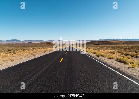 Die Straße verschwindet in der Ferne in der Wüstenlandschaft. Stockfoto