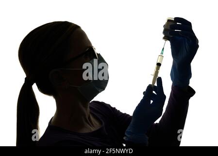 Krankenschwester bereitet sich auf die Impfung eines Patienten mit einem Coronavirus-Impfstoff vor, der vor weißem Hintergrund silhouettiert wird Stockfoto