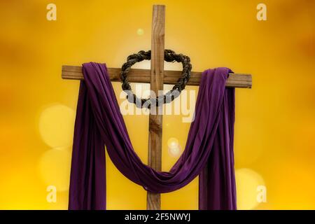 Holzkreuz mit Dornenkrone und violettem Stoff, katholische Symbole, Zeit der Fastenzeit Stockfoto